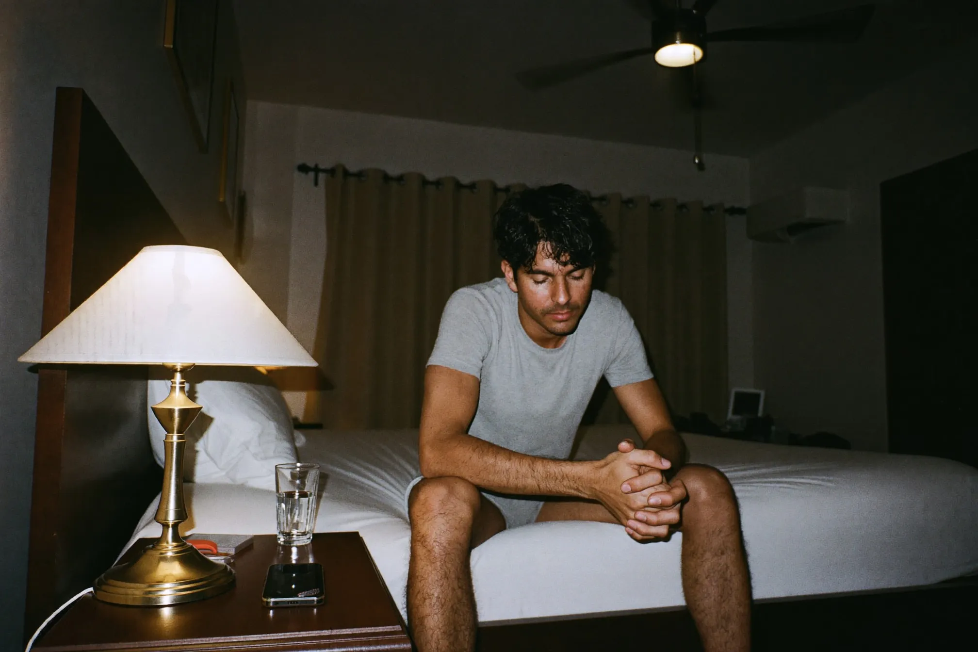 Man winding down in a dim bedroom at night with his phone face down on the nightstand