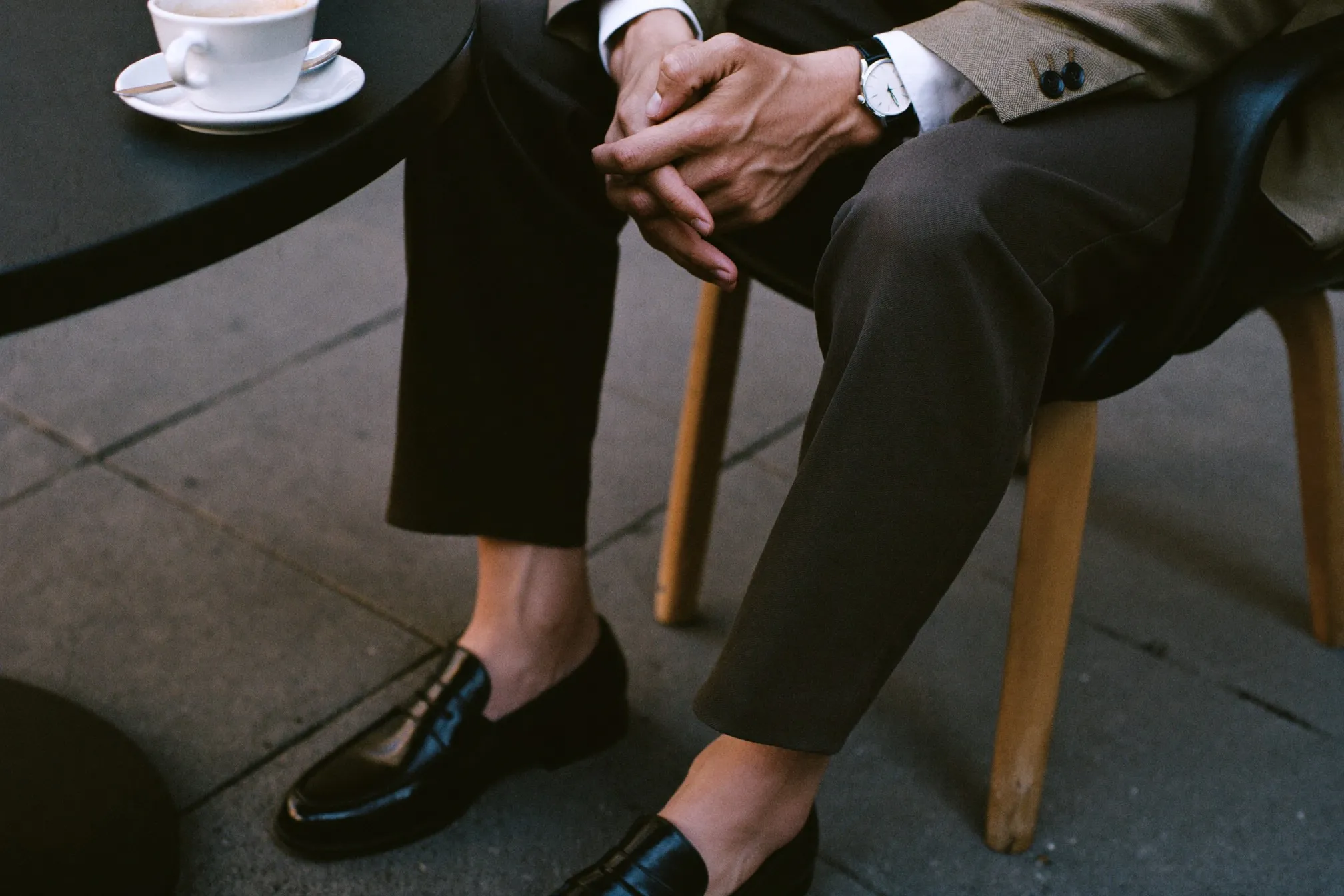 Close view of smart casual details: watch, unstructured blazer cuff, dark chinos and suede loafers