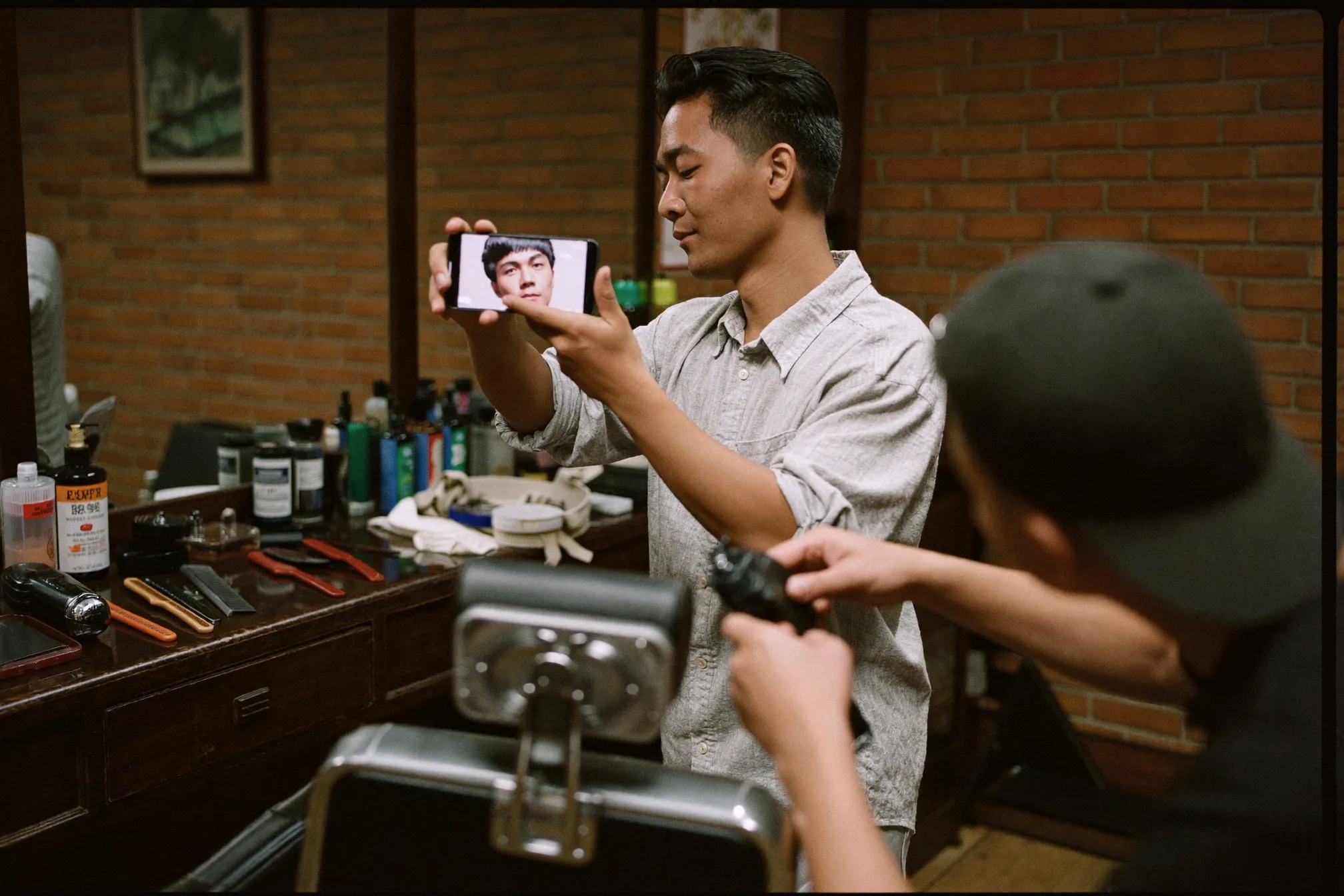 Man holding up his phone to show a barber a reference haircut photo before the cut starts