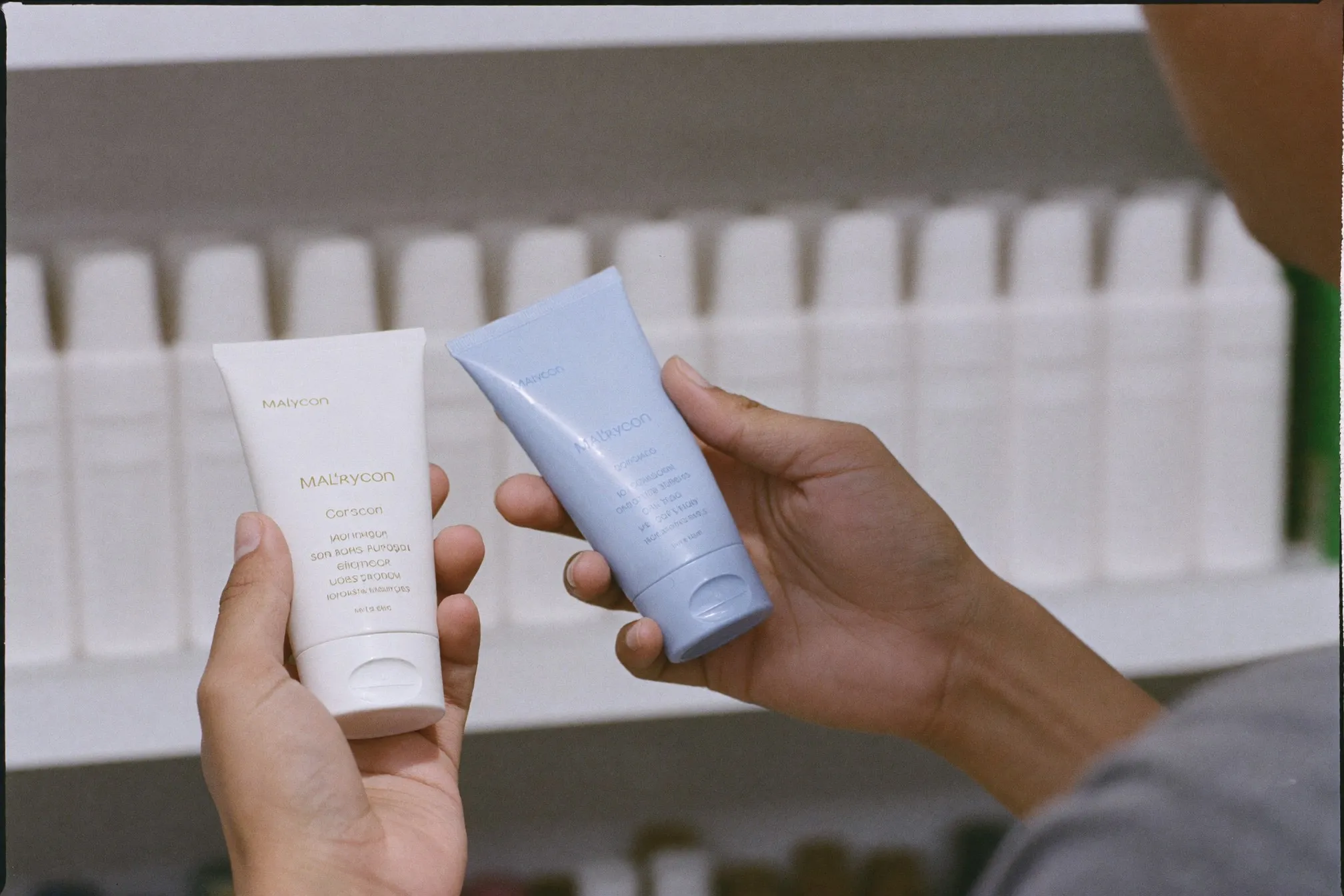 Close view of a man's hands holding two unbranded sunscreen bottles under bright shelf lighting