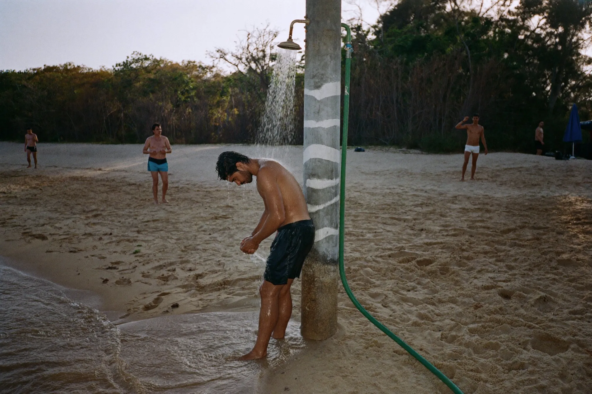 Man rinsing off at an outdoor beach shower after a swim on the Malaysian coast