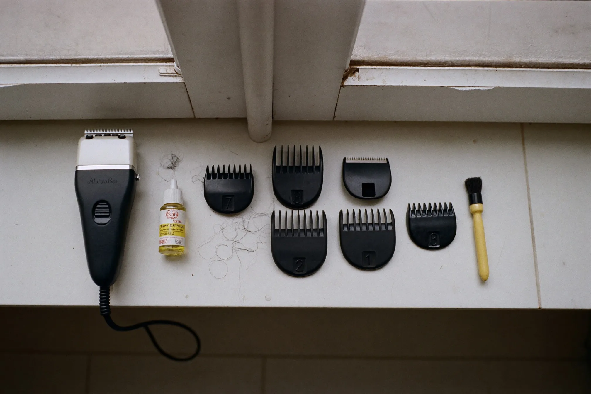 Set of numbered plastic clipper guards laid out next to a cordless hair clipper on a bathroom counter