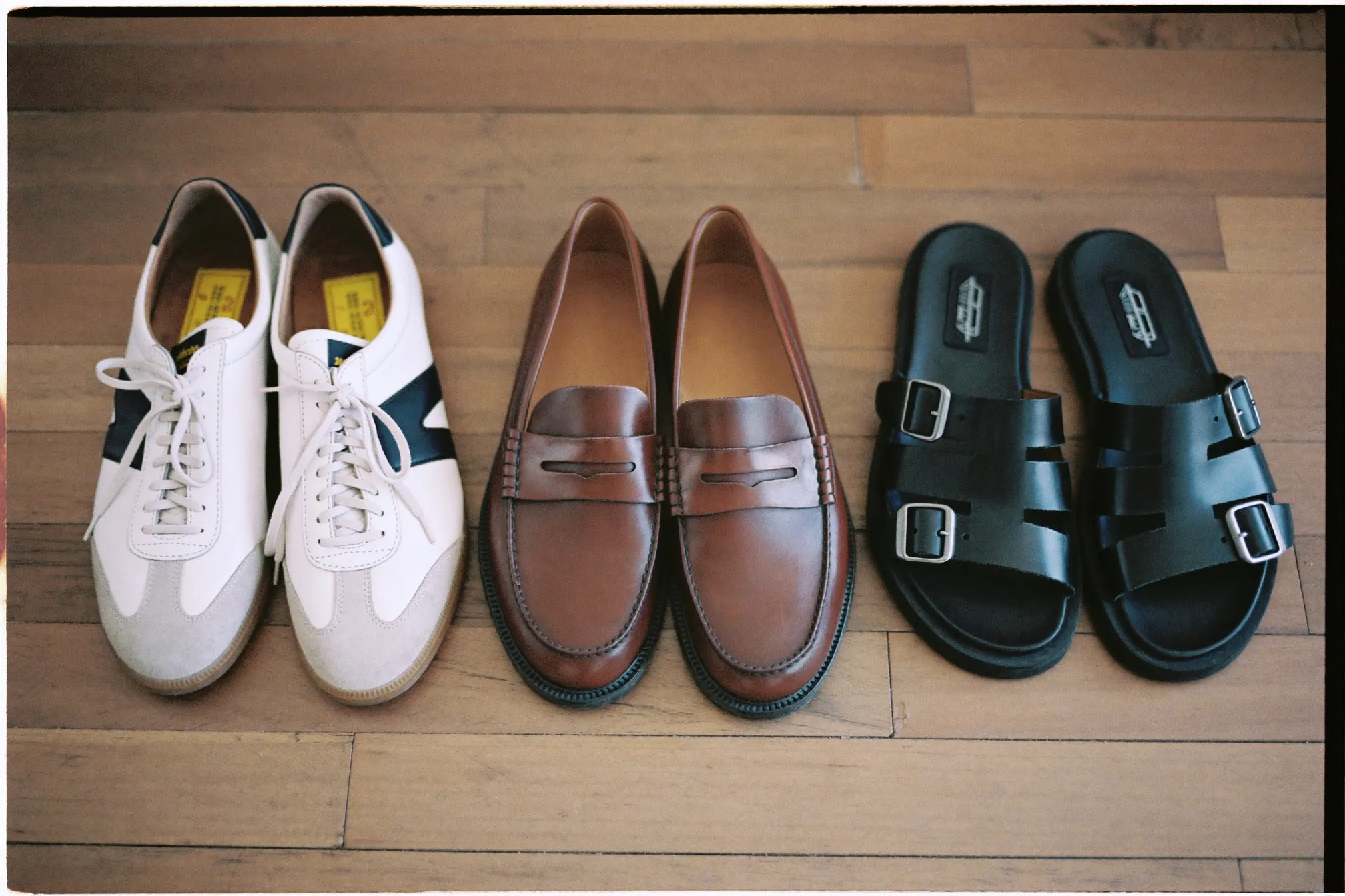 Four pairs of shoes in a row: sneakers, loafers, derbies, sandals