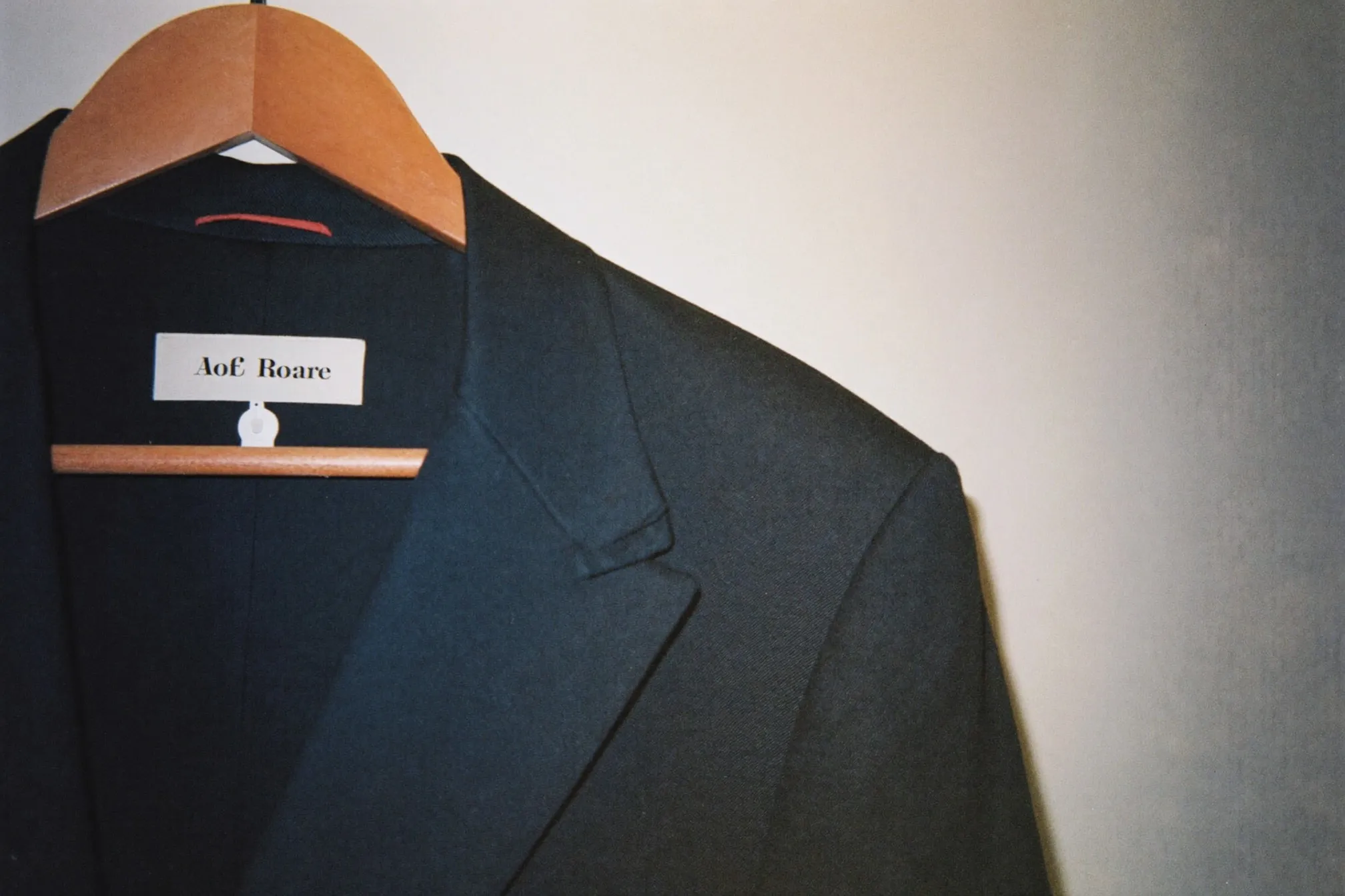 Unstructured navy blazer on a wooden hanger