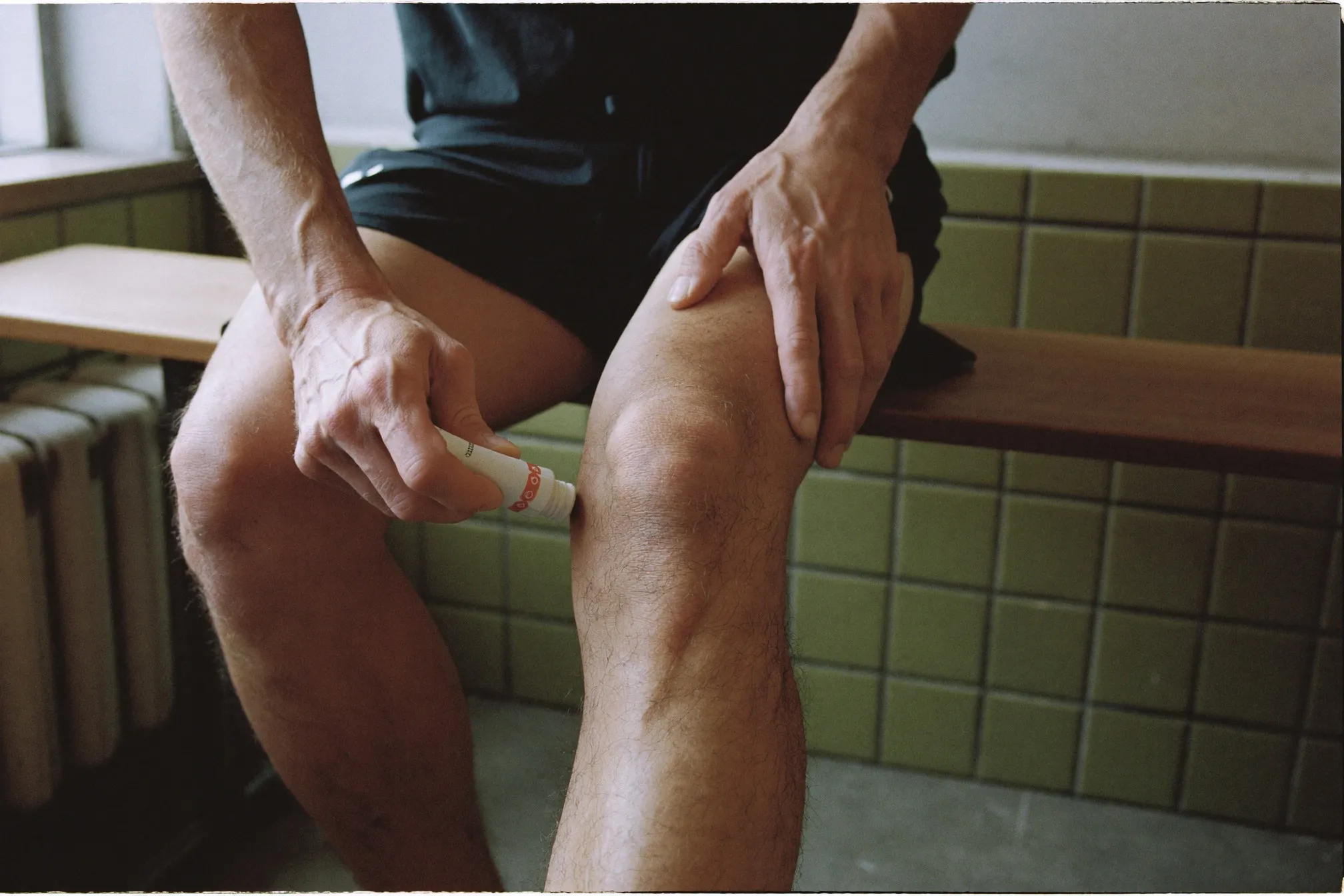 Close view of a man's hands applying an unbranded anti-chafing balm stick to his inner thigh before a run