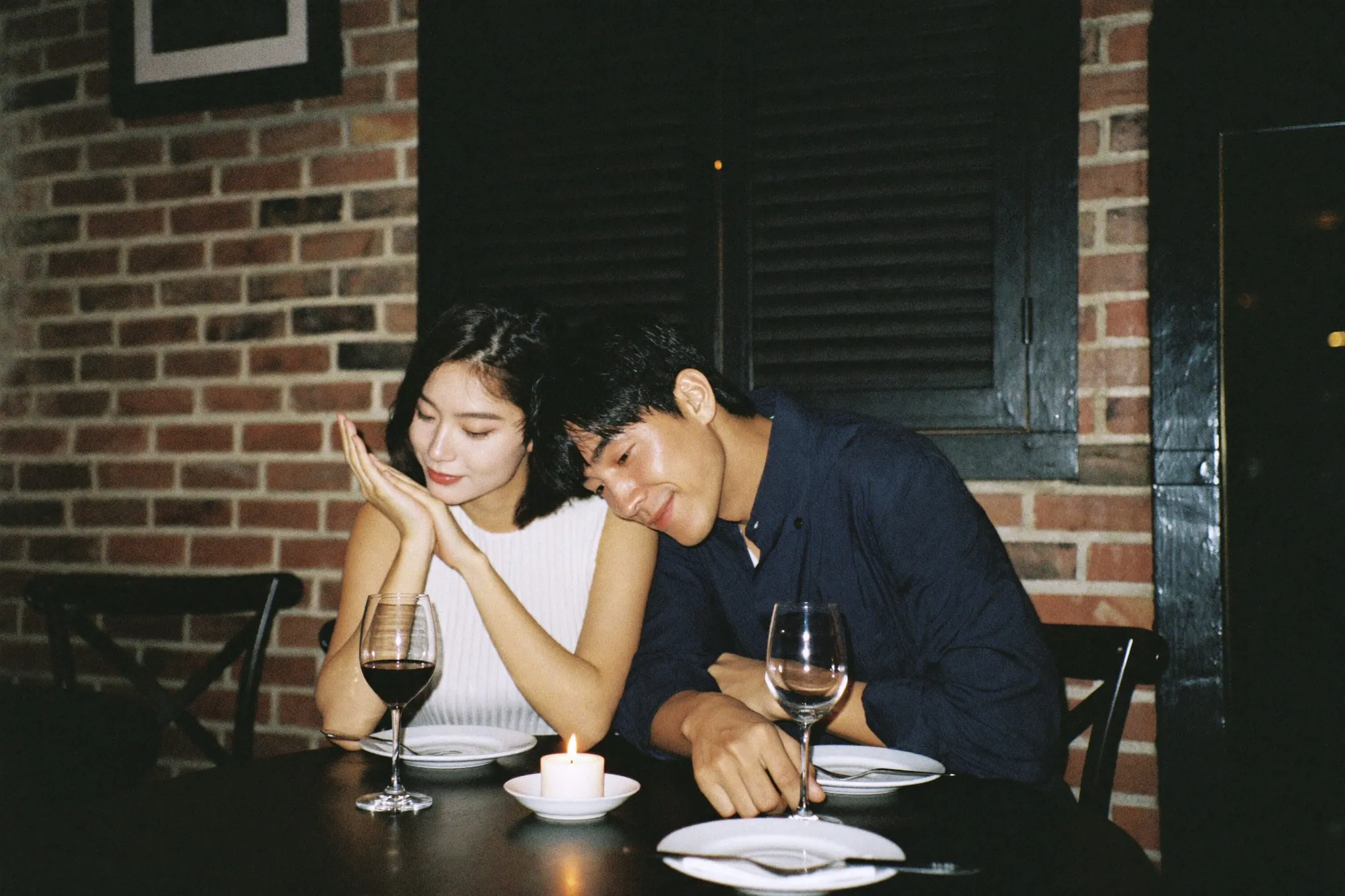 Couple at a candlelit restaurant table in a Singapore shophouse, warm indoor lighting