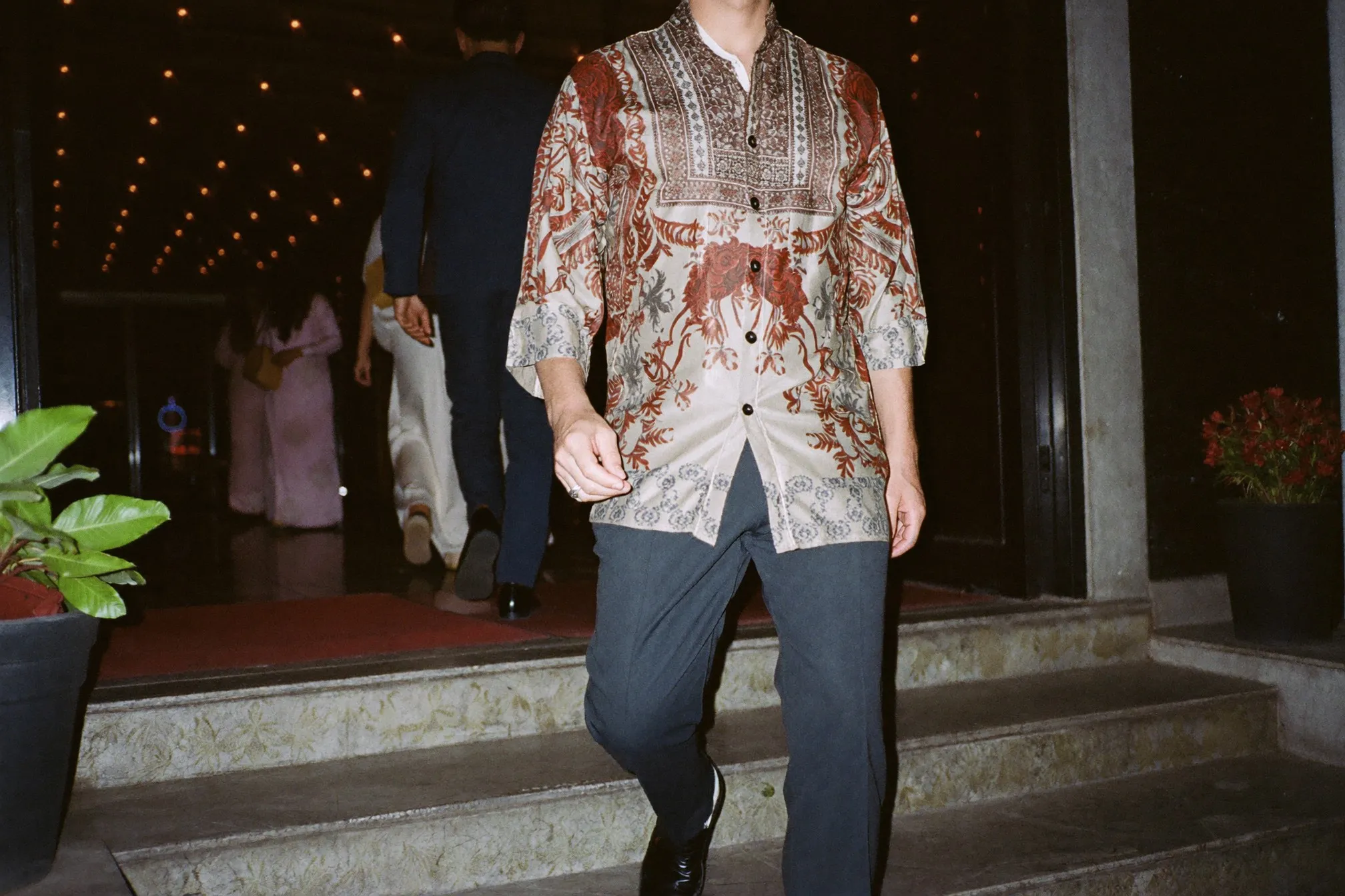 Man in a long-sleeved batik shirt and dark trousers arriving at an evening function in Kuala Lumpur