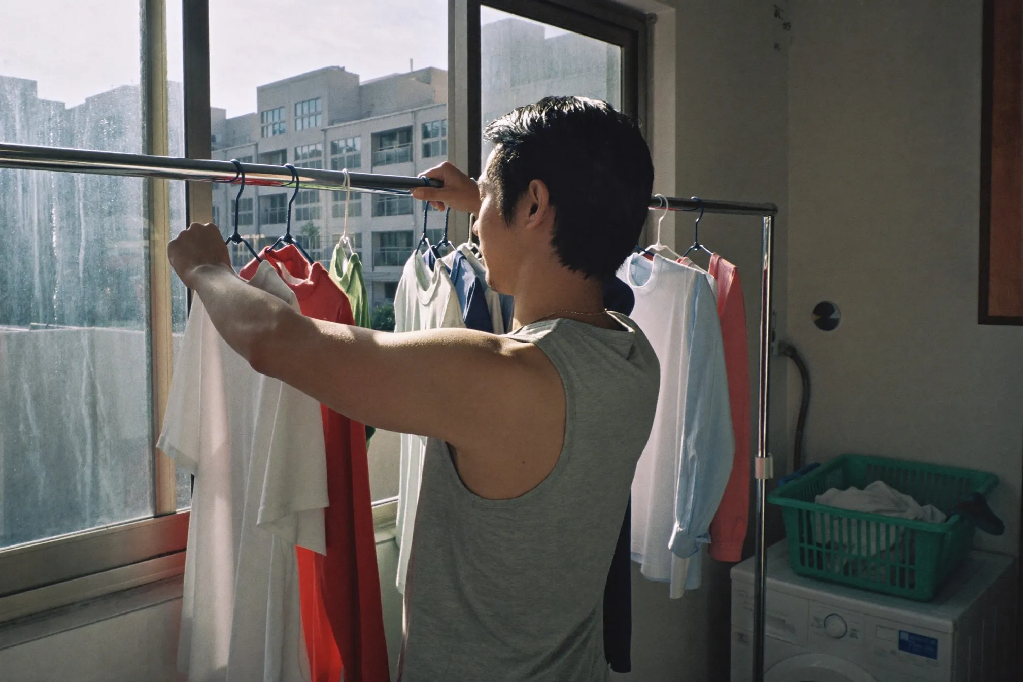 Man hanging loose cotton shirts on a laundry rack at an HDB service yard window