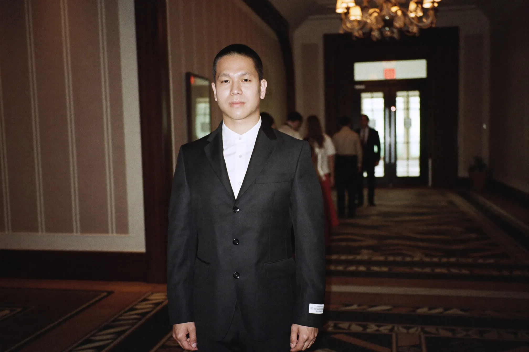 Man in a dark suit in a hotel ballroom foyer in the evening before a wedding dinner