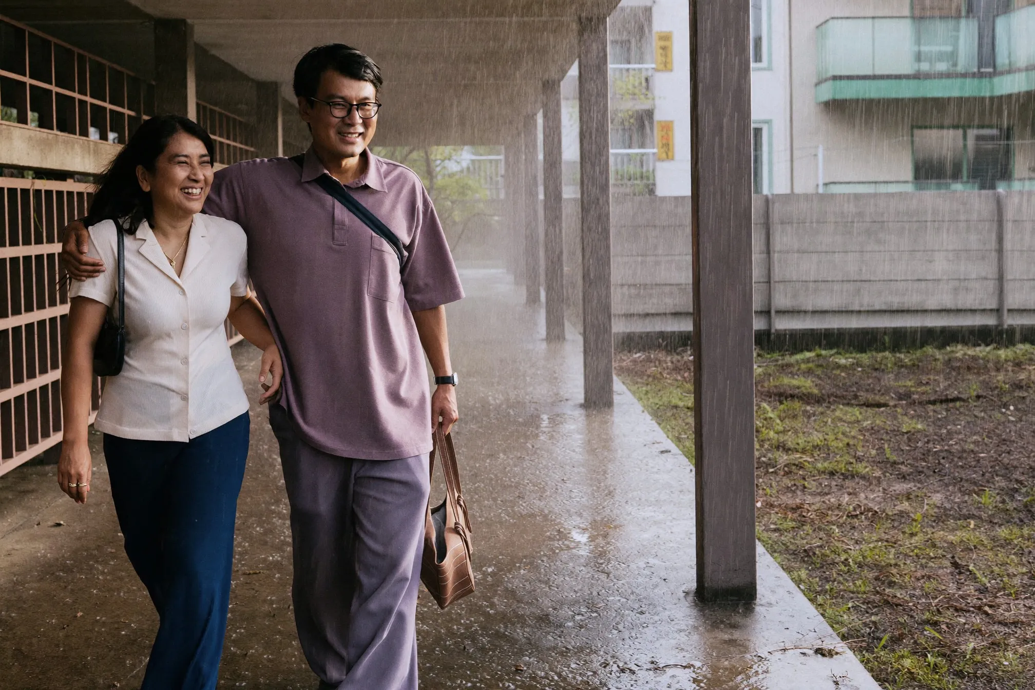 A couple walking through a covered walkway during heavy afternoon rain in Singapore
