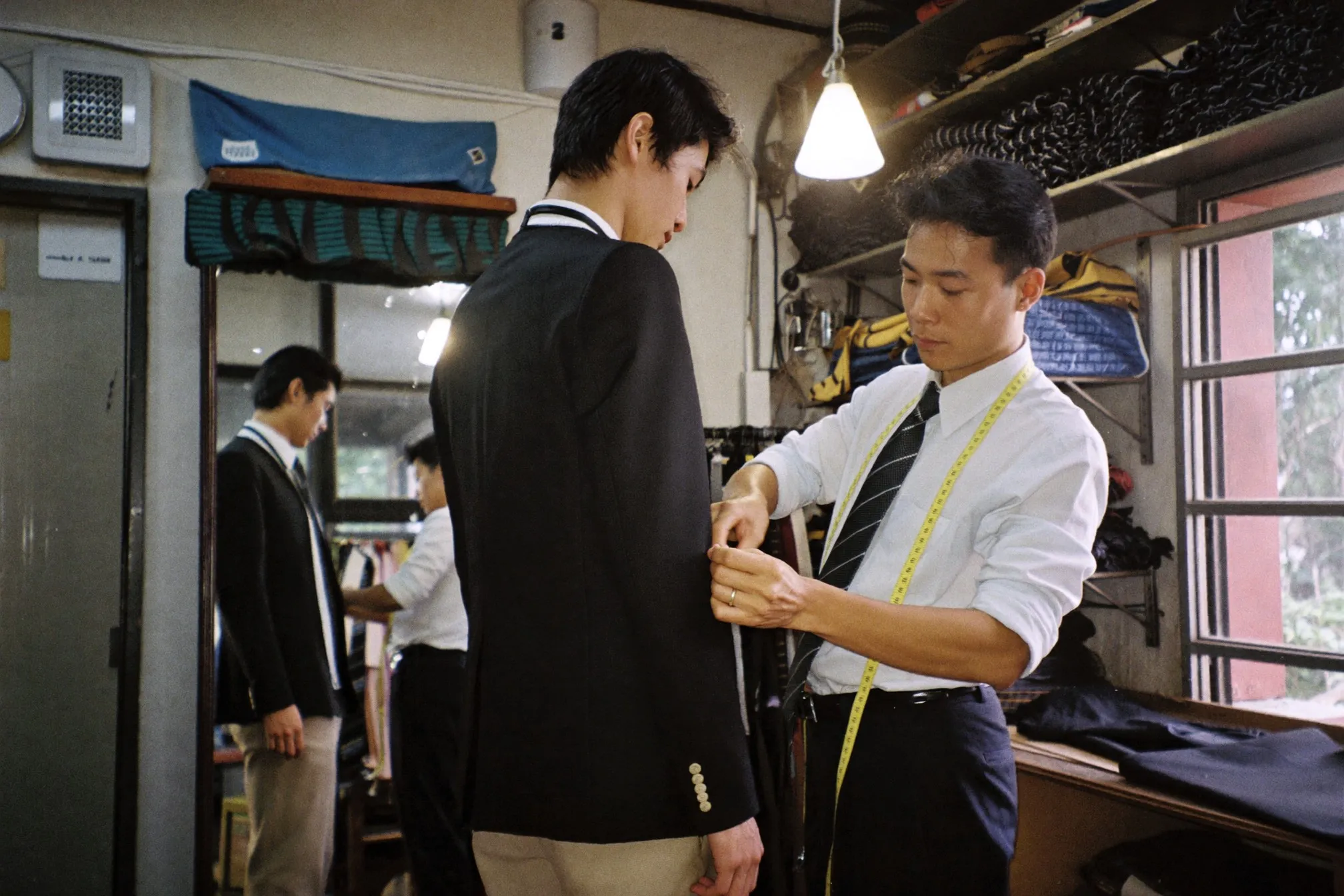 Tailor pinning the sleeve of a dinner jacket on a client during a fitting in a small tailor shop