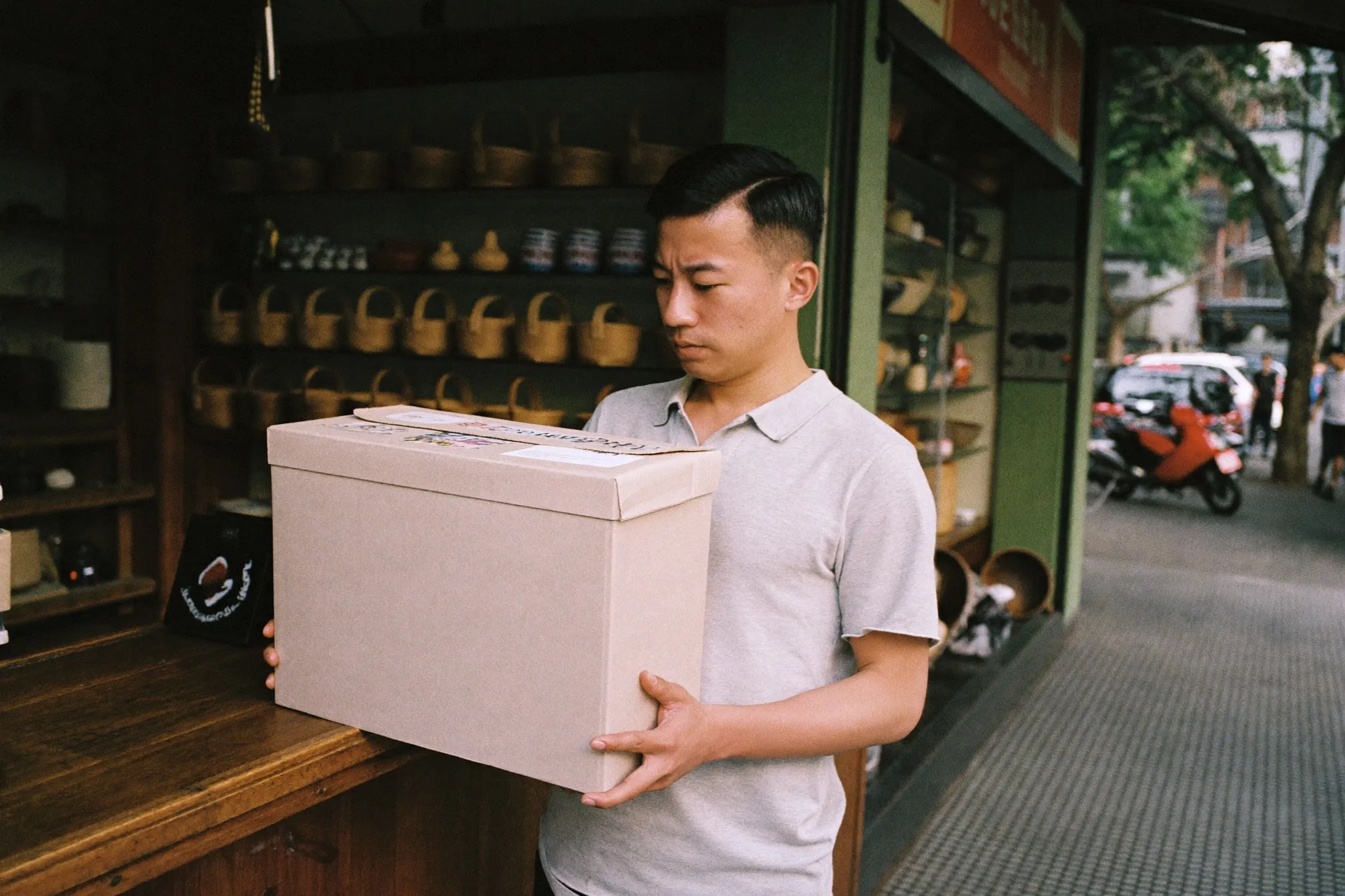 A man in his late twenties choosing a small gift at the counter of an independent homeware shop in a Kuala Lumpur shophouse