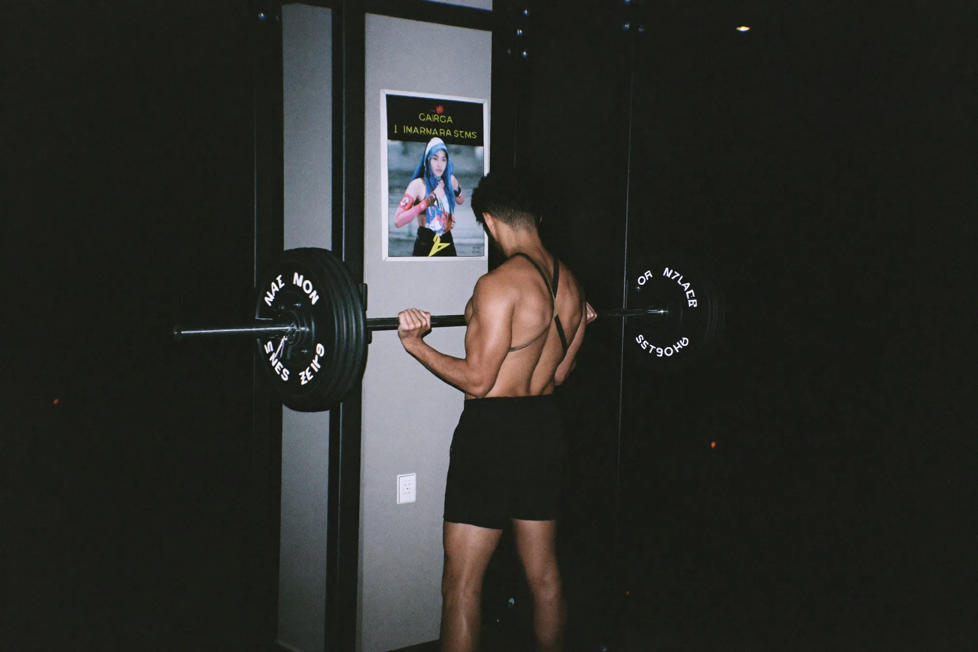 Man training alone at a dumbbell rack in a quiet neighbourhood gym at night