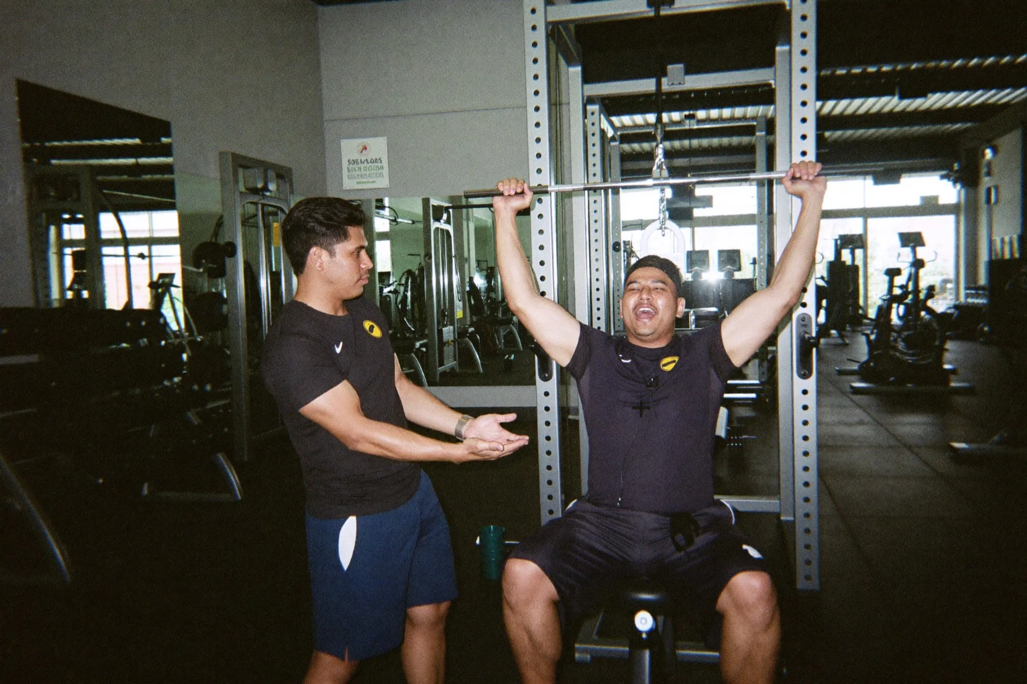 A trainer coaching a man through a goblet squat in a bright gym in Singapore