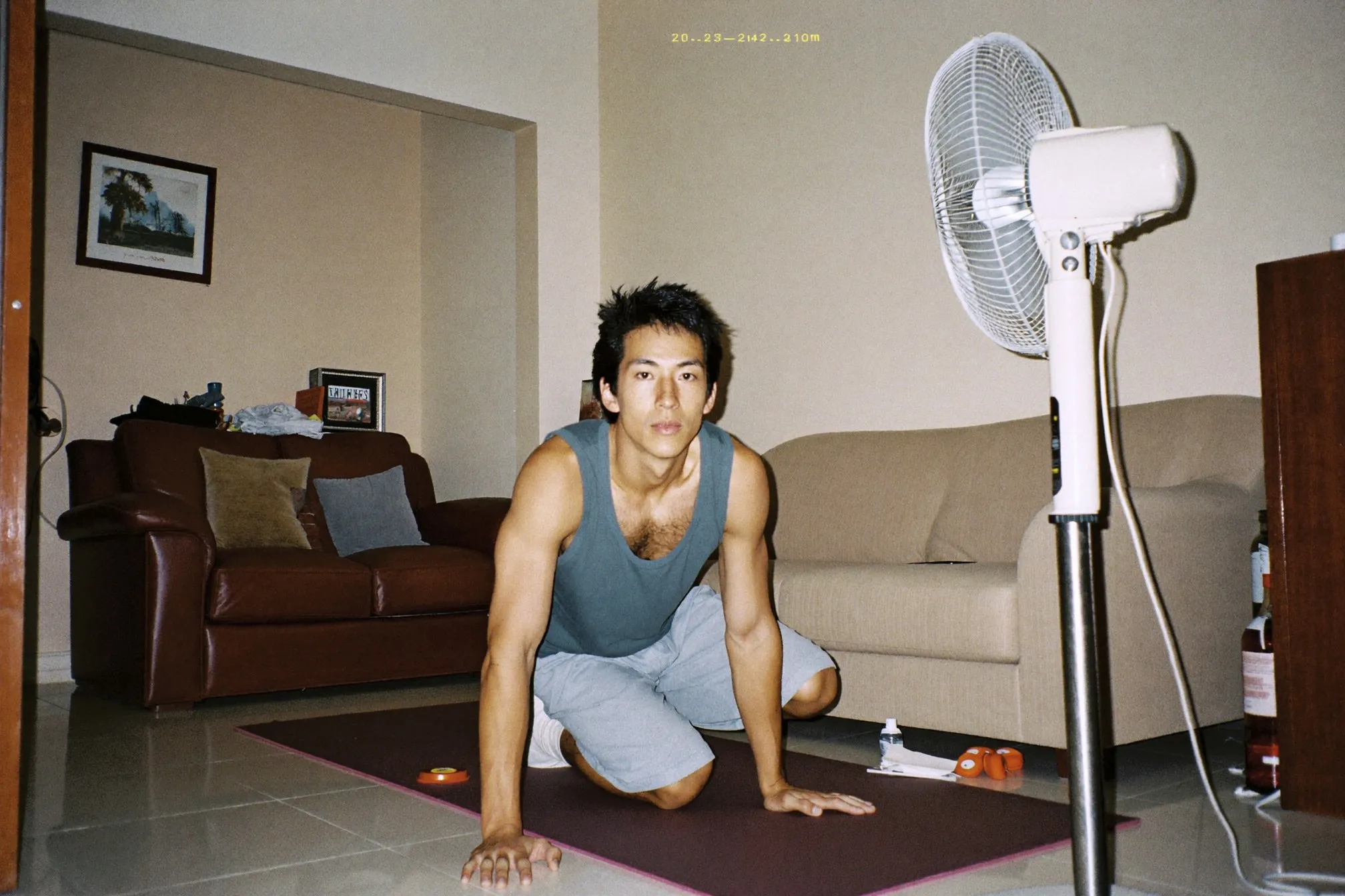 Chinese Malaysian man mid mountain climber on a mat in a small Kuala Lumpur condo living room with a standing fan running