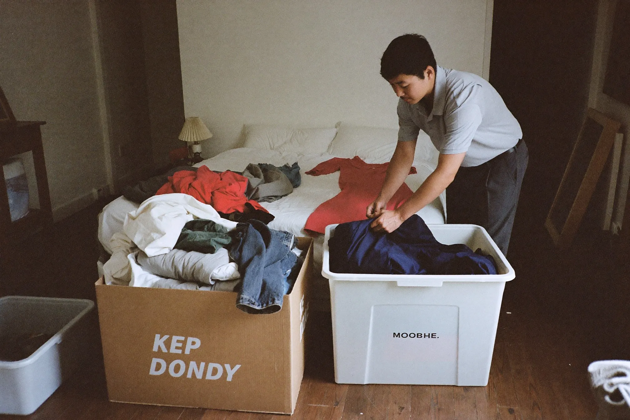 Man sorting clothes on a bed into keep and donate piles