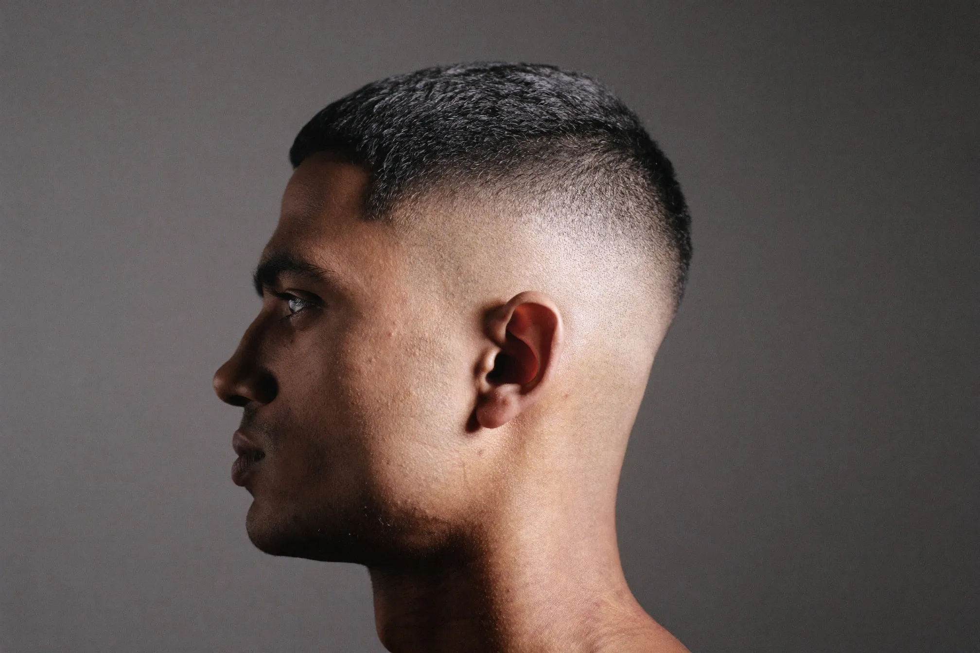 Side profile of an Indian Singaporean man showing the tapered back and sides of a crew cut with longer hair left at the front