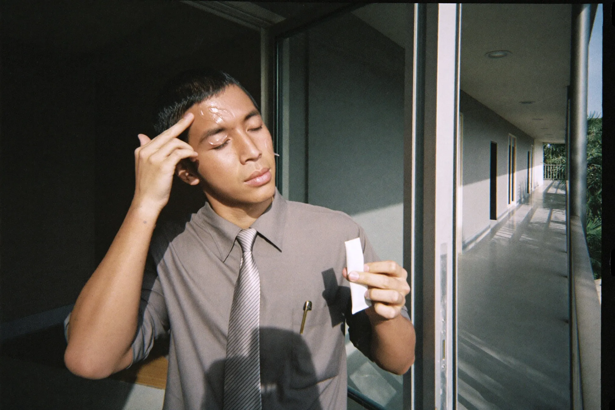 Man applying a light sunscreen fluid at his front door before leaving for work