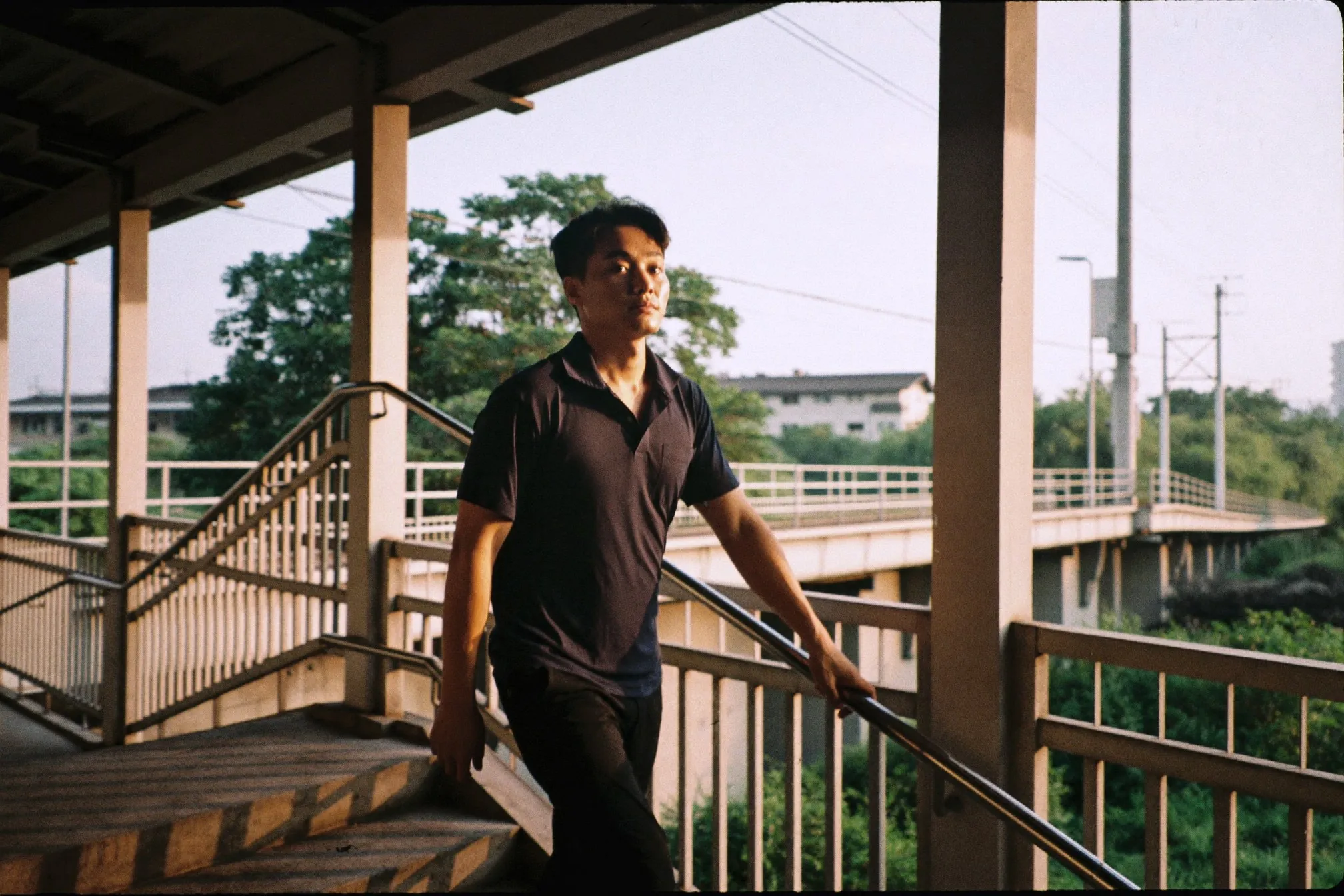 Man walking briskly up a covered pedestrian staircase near an MRT station in the early morning