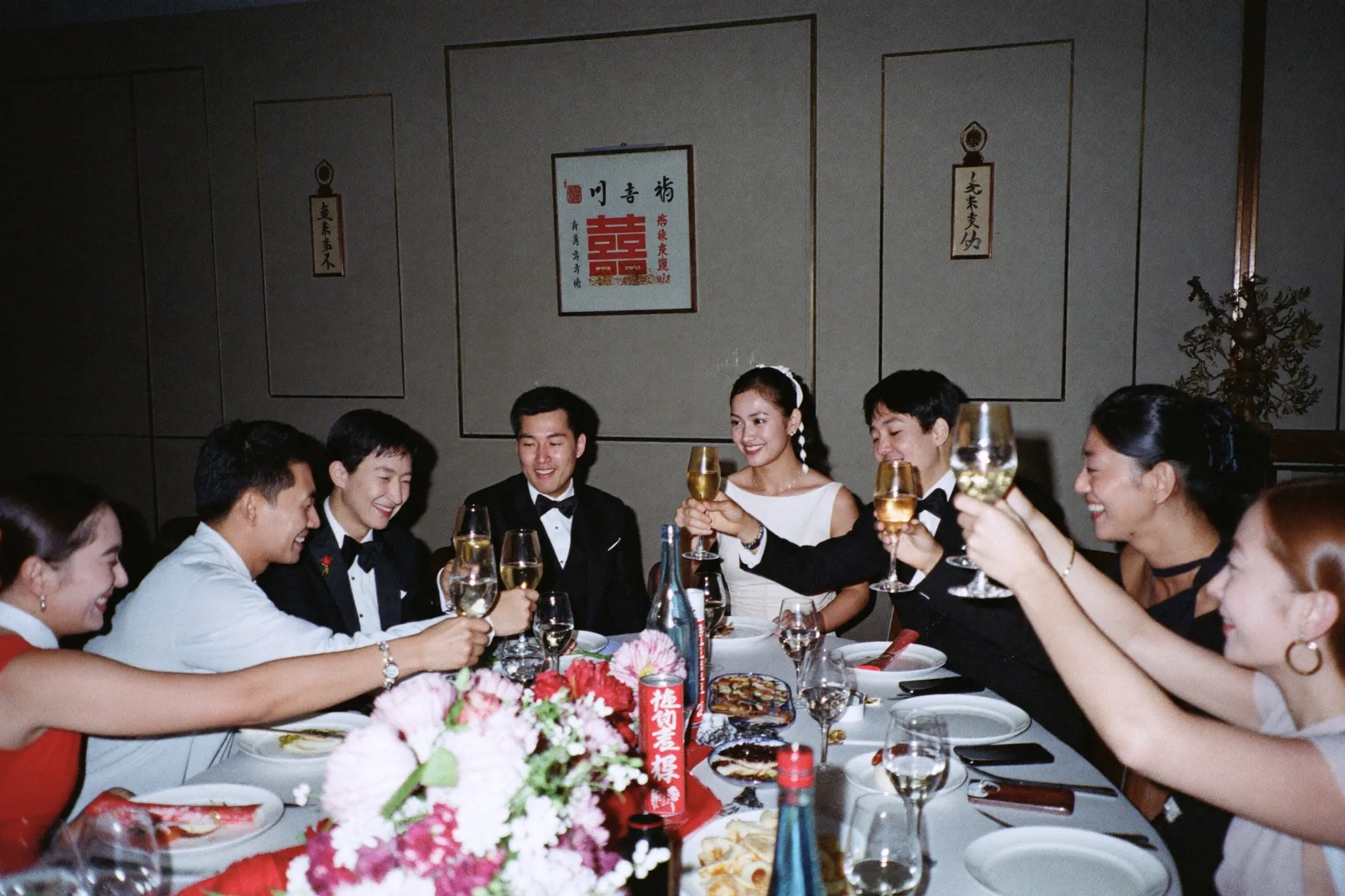 Round banquet table with friends toasting at a Chinese wedding dinner in a ballroom