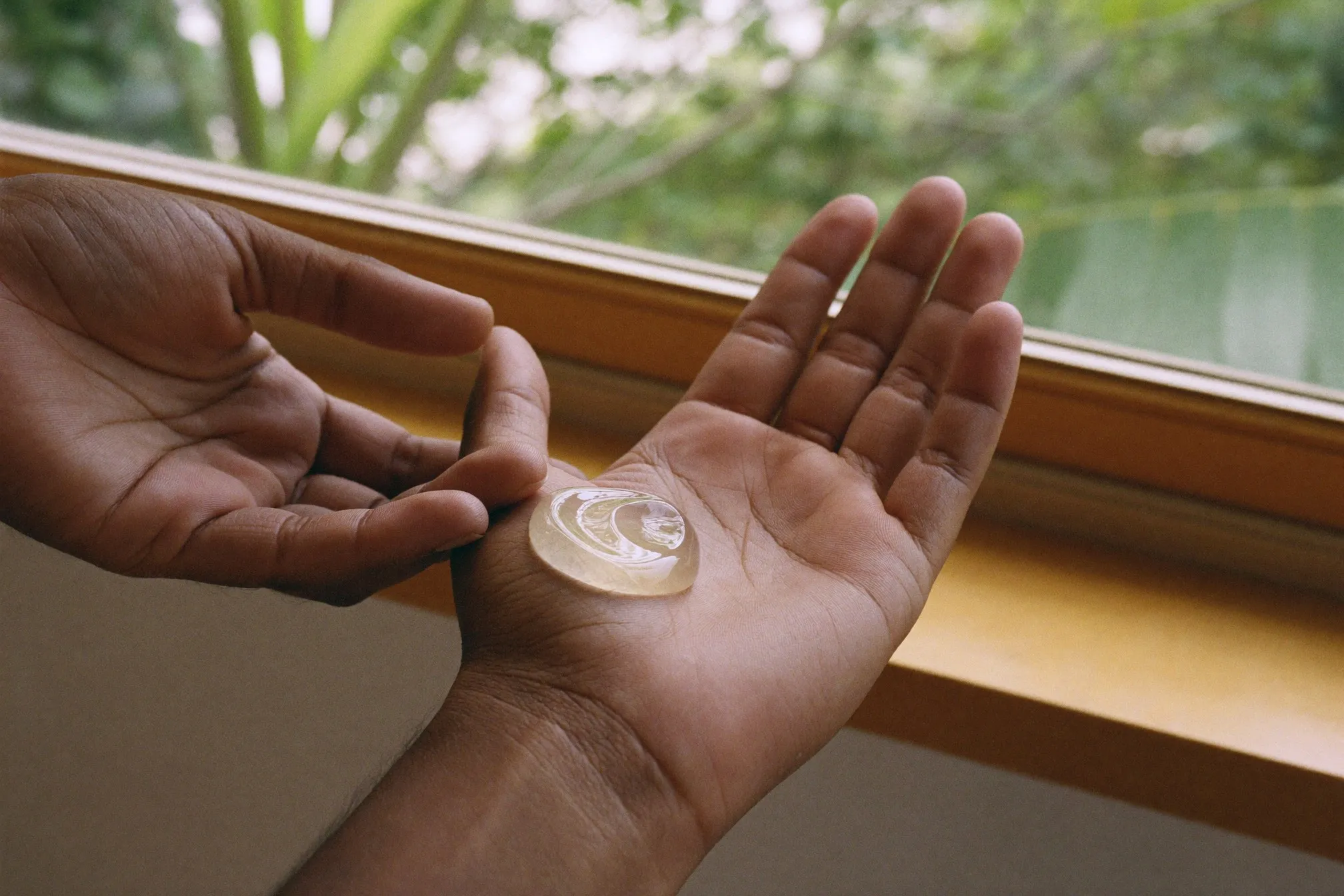 Dollop of clear gel moisturiser on the back of a man's hand near a bright window