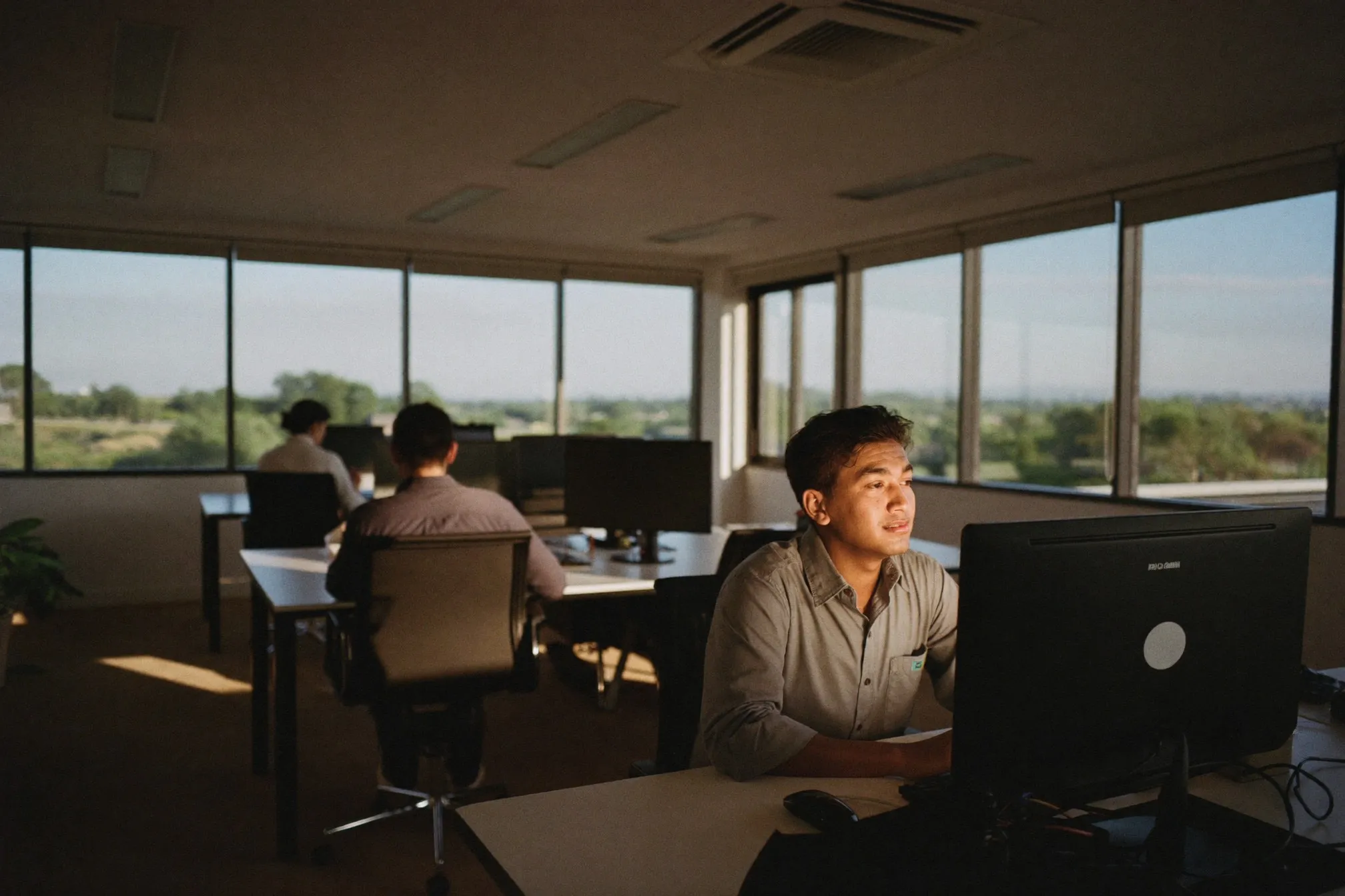 Man working at a desk in a shared open-plan office in Singapore in the late afternoon