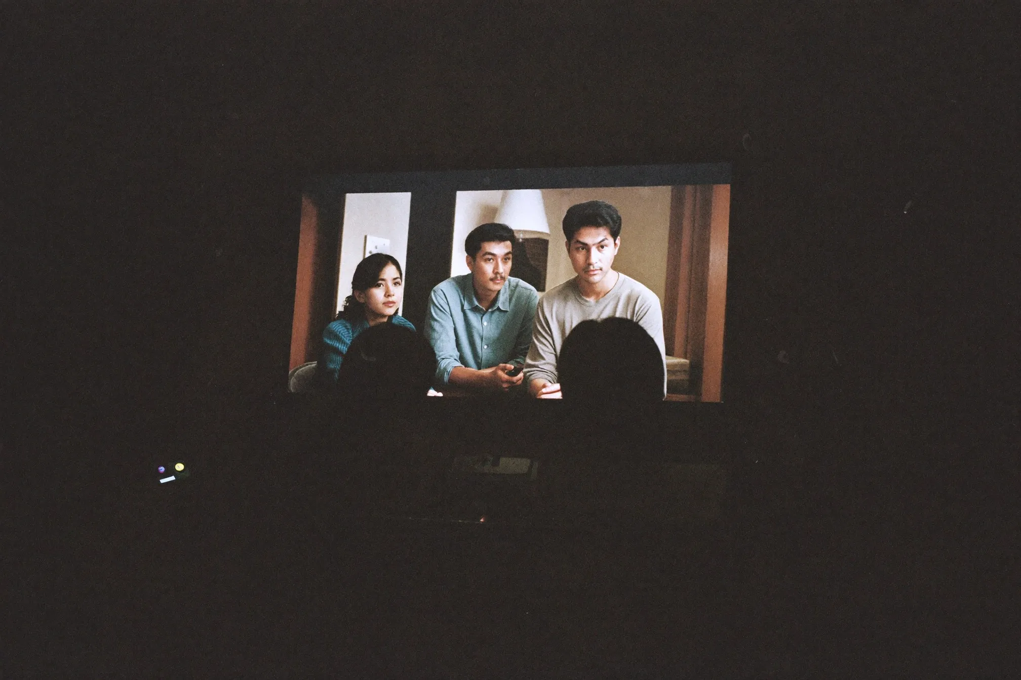 Friends watching a film in a dim living room, faces lit by the screen