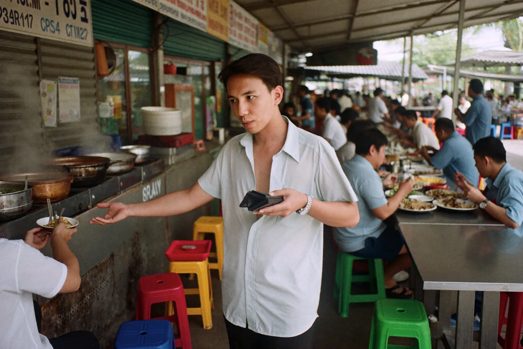 Man queuing to buy food at a hawker centre stall during a weekday lunch break