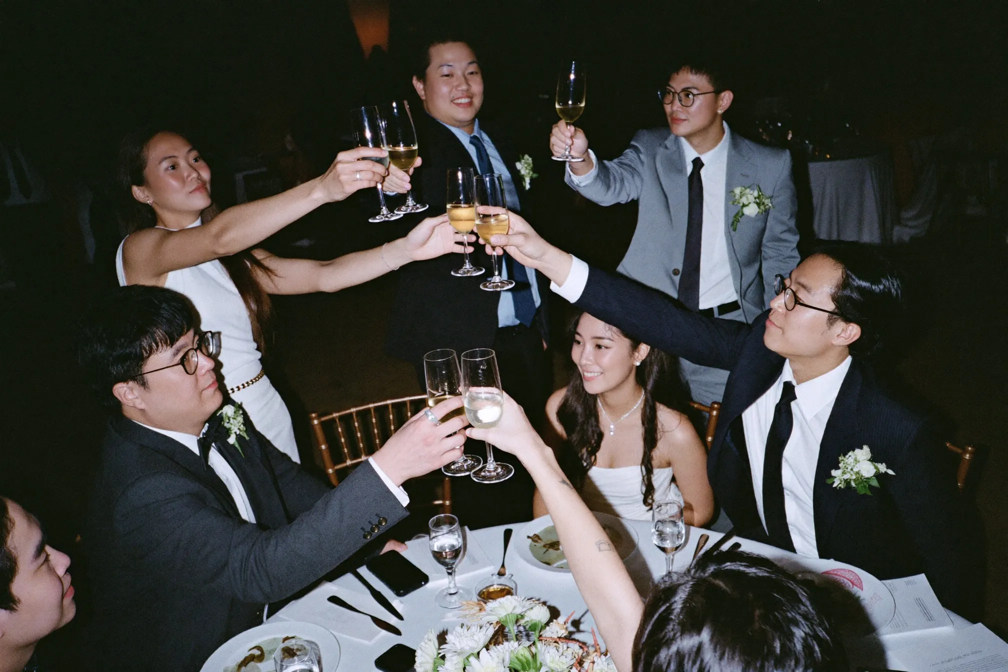 Friends raising glasses in a toast at a wedding banquet