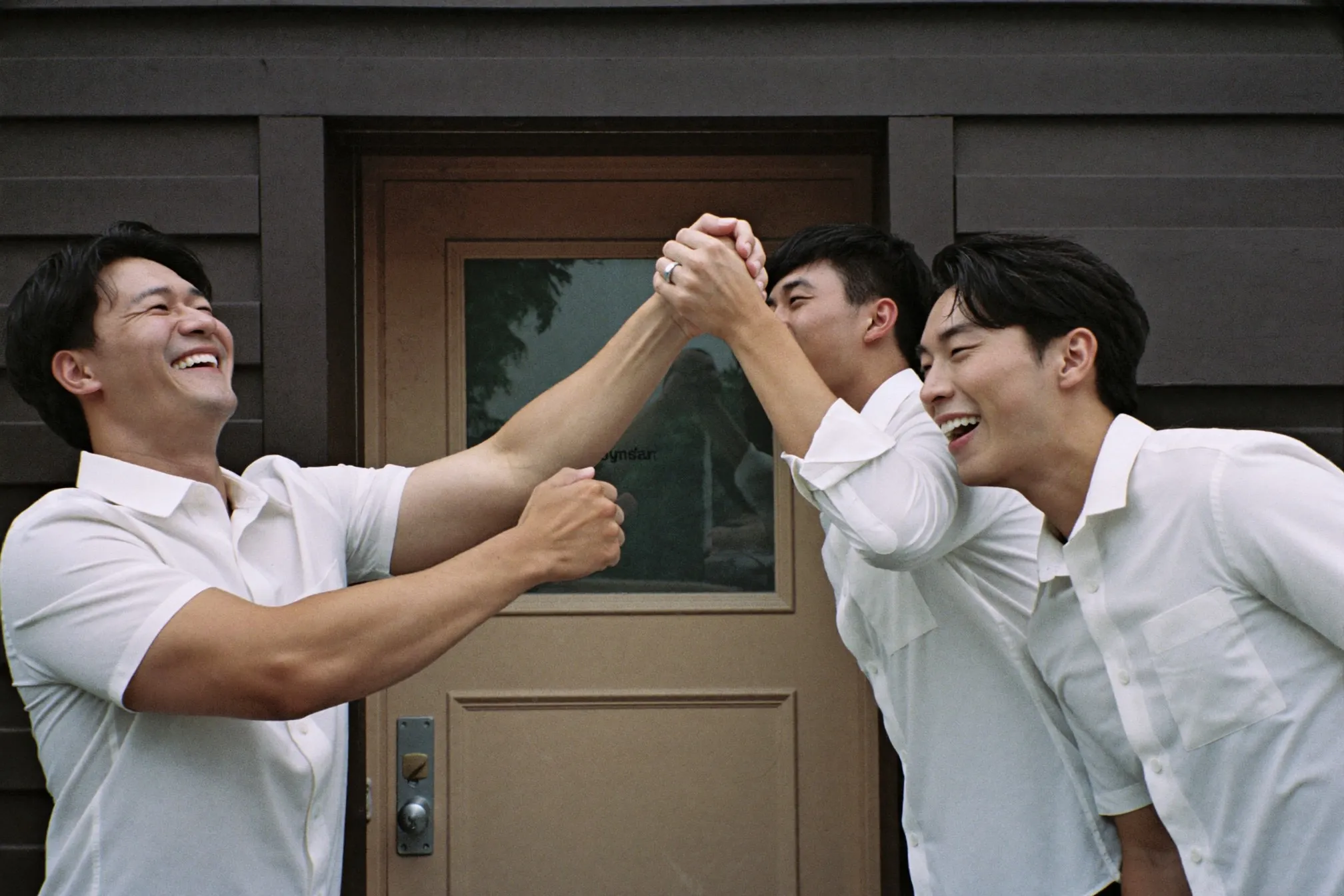 Groomsmen laughing during morning door games outside an HDB door