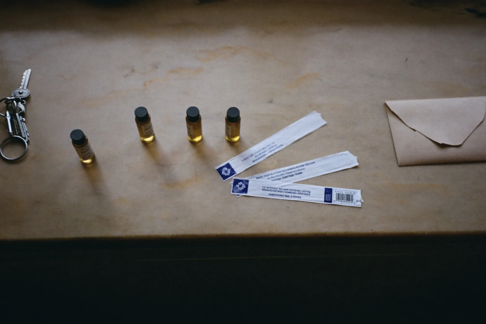 Small unlabelled amber glass decant vials and used blotter strips on a stone counter in daylight