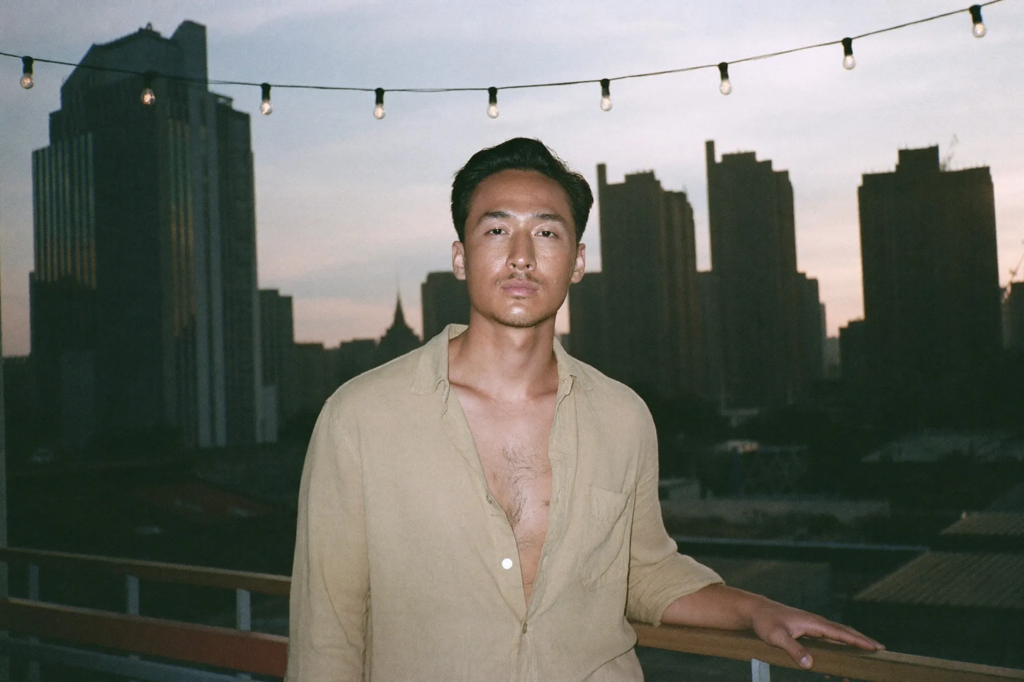 Man in a linen shirt at an outdoor rooftop bar in Singapore in the evening heat