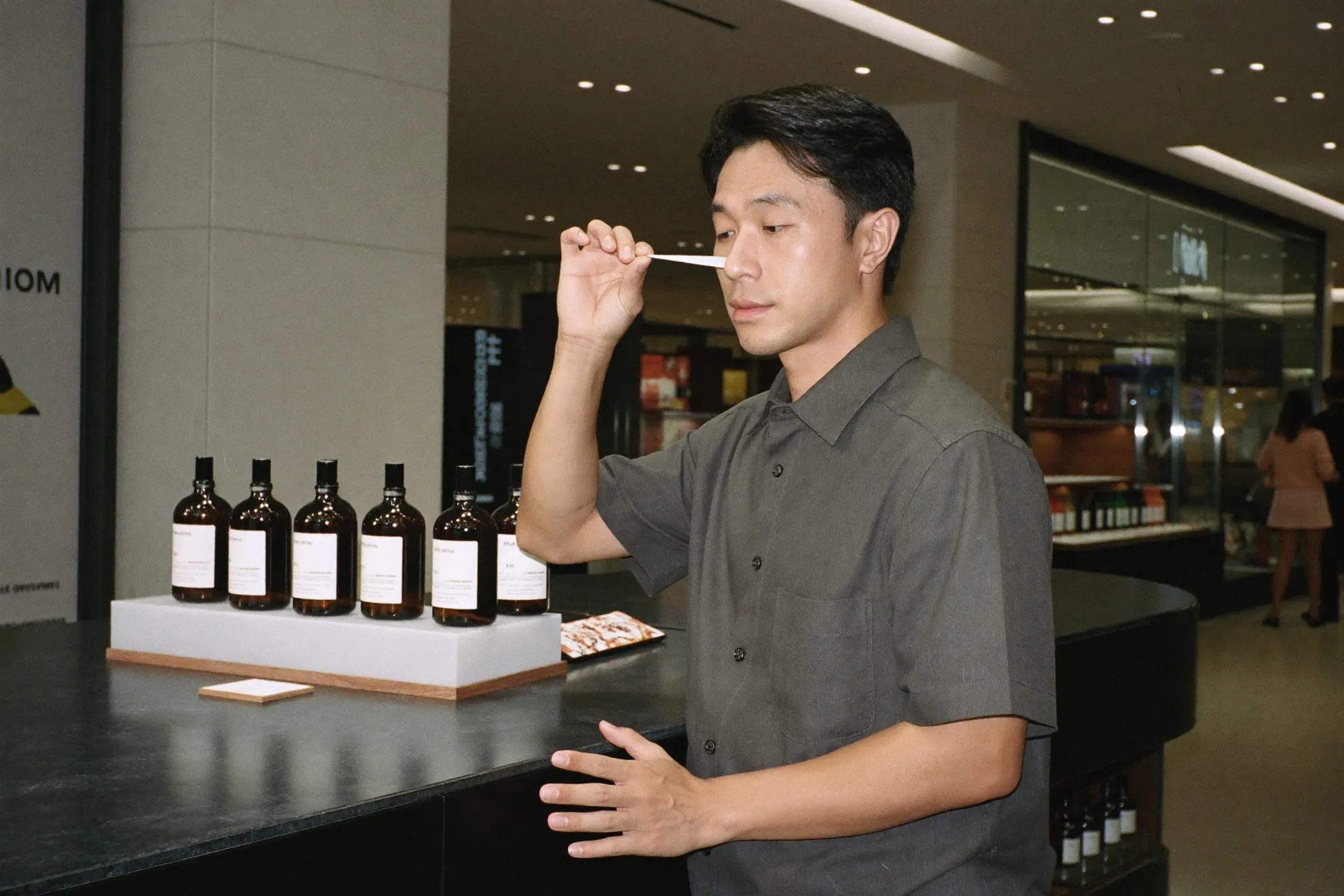 Man at a department store fragrance counter in Kuala Lumpur holding a paper test strip to his nose