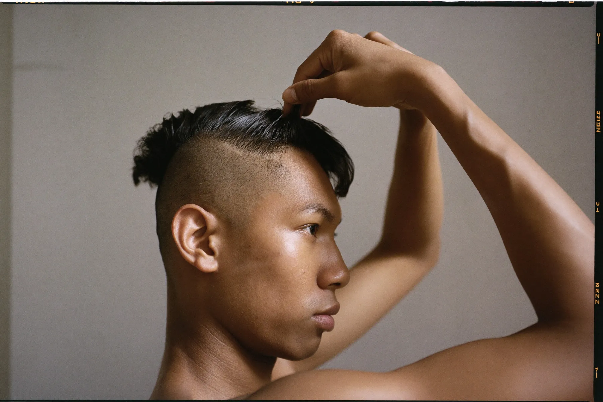 Side profile of a young Indian man with the long top of his two block haircut lifted to show the short disconnected section above his ear