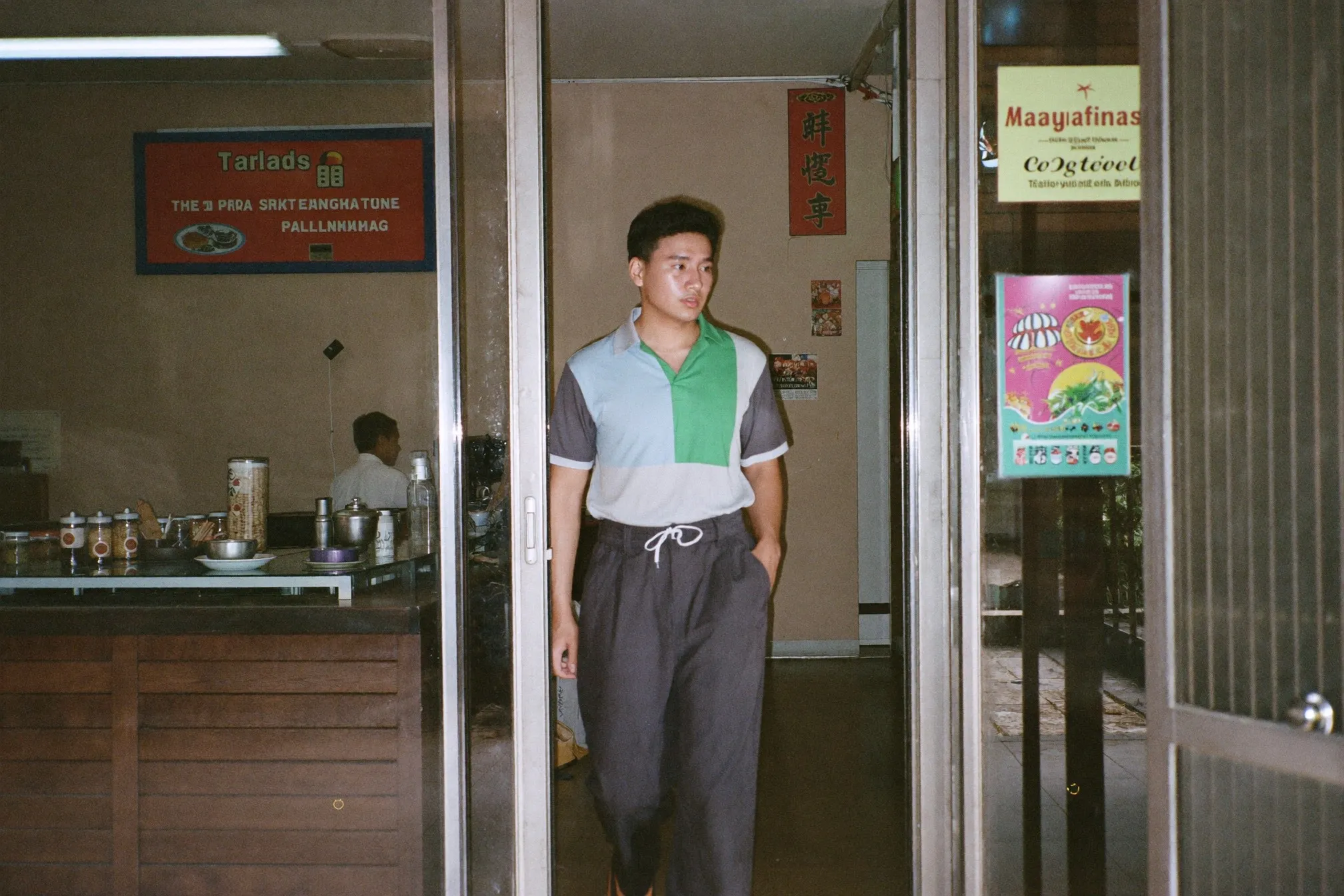 Man in a polo and drawstring trousers walking to a kopitiam downstairs from his flat at lunchtime